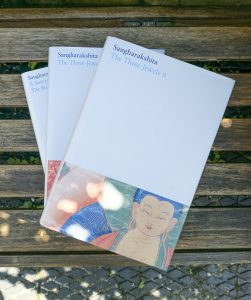 three books set on a brown bench in the shade