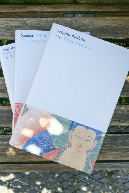 three books set on a brown bench in the shade