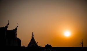 setting sun in the background with thai temples on the left